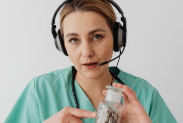 Medical professional in green scrubs holding medicine bottle during online consultation, highlighting telemedicine communication.